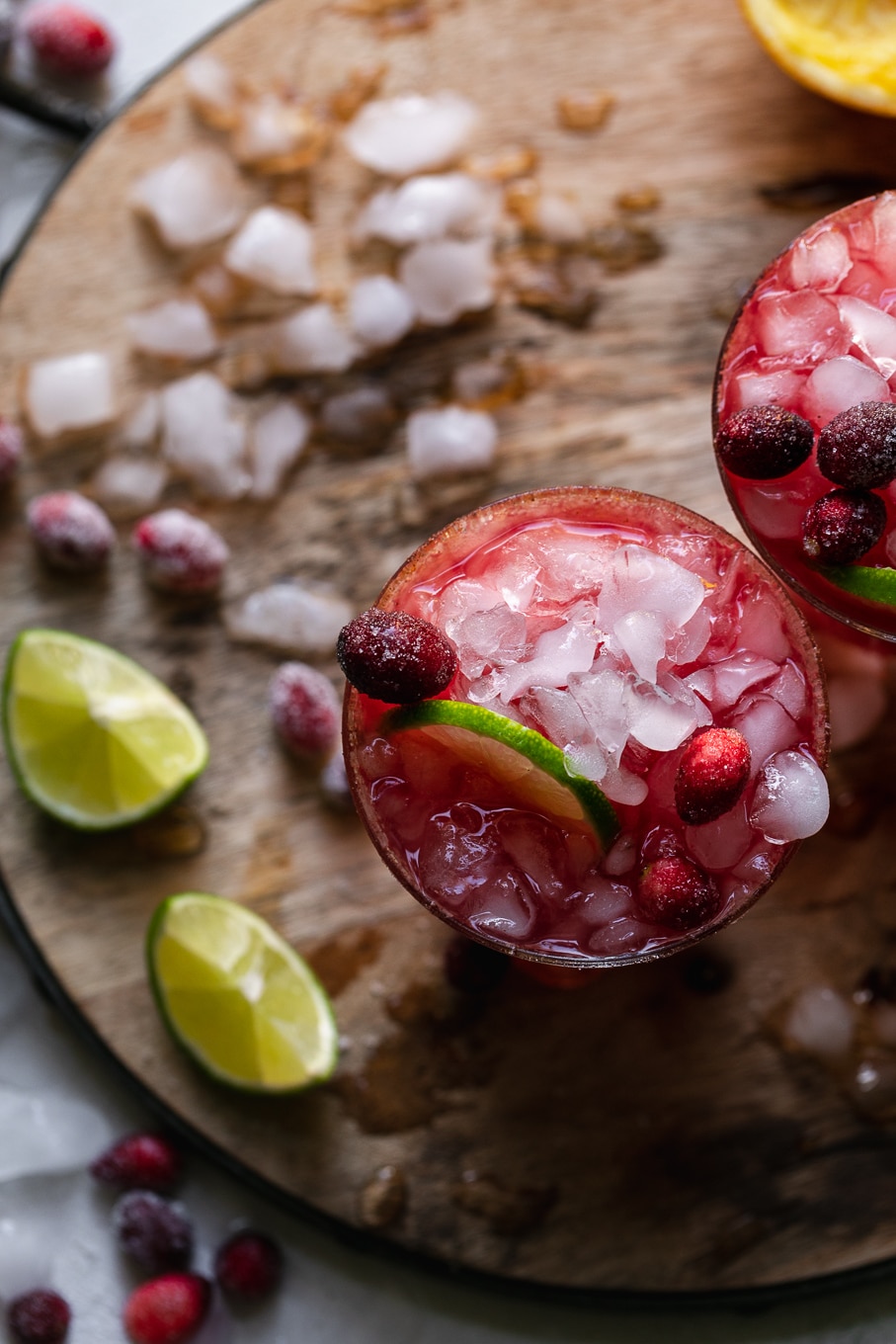 Overhead shot of two cranberry margaritas on a wooden board