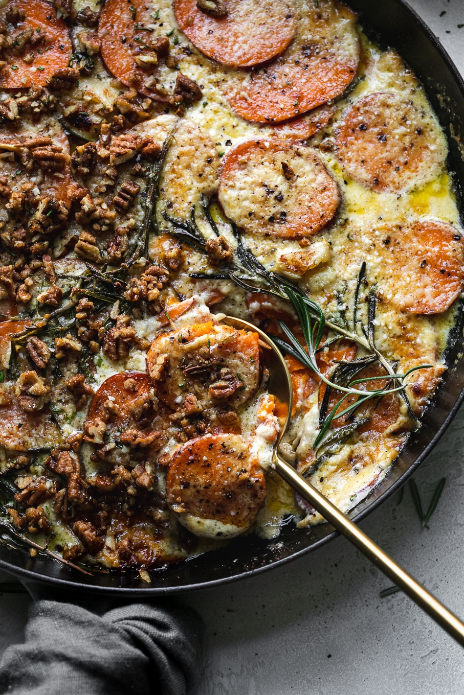 Overhead close up shot of sweet potato gratin with a gold spoon digging in