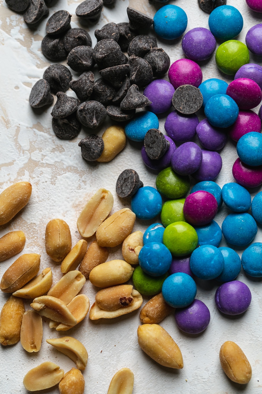 Super close up shot of peanuts, colorful candy coated chocolate pieces, and chocolate chips