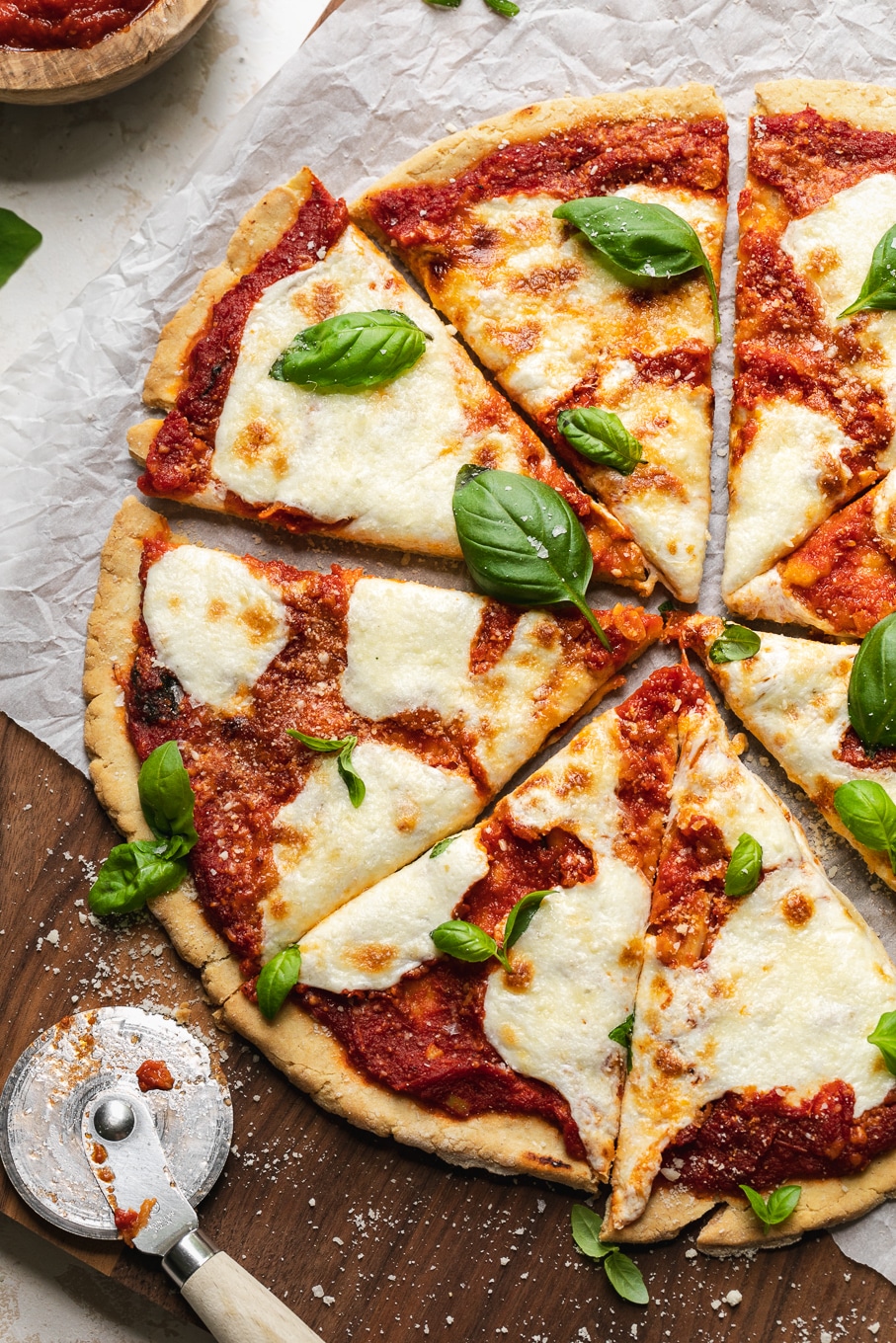 Overhead shot of a pizza cut into slices with fresh basil