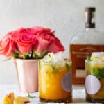Straight on shot of peach basil cocktails with roses in the background