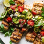Close up shot of grilled salmon topped with greek salad